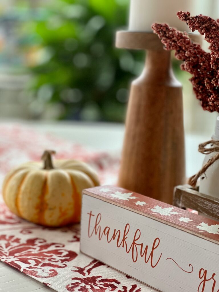 Jess Ronne shares an excerpt from Blended with Grit and Grace, where she talks about how gratitude shifts our perspectives. Image is of fall table placement, with a book that says "thankful" on the side, a ceramic punpkin, and a vase. Photo by Stephanie Klepacki on Unsplash