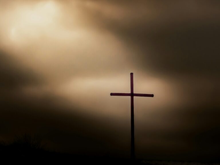 warm image of a cross that is backlit with night around the ground