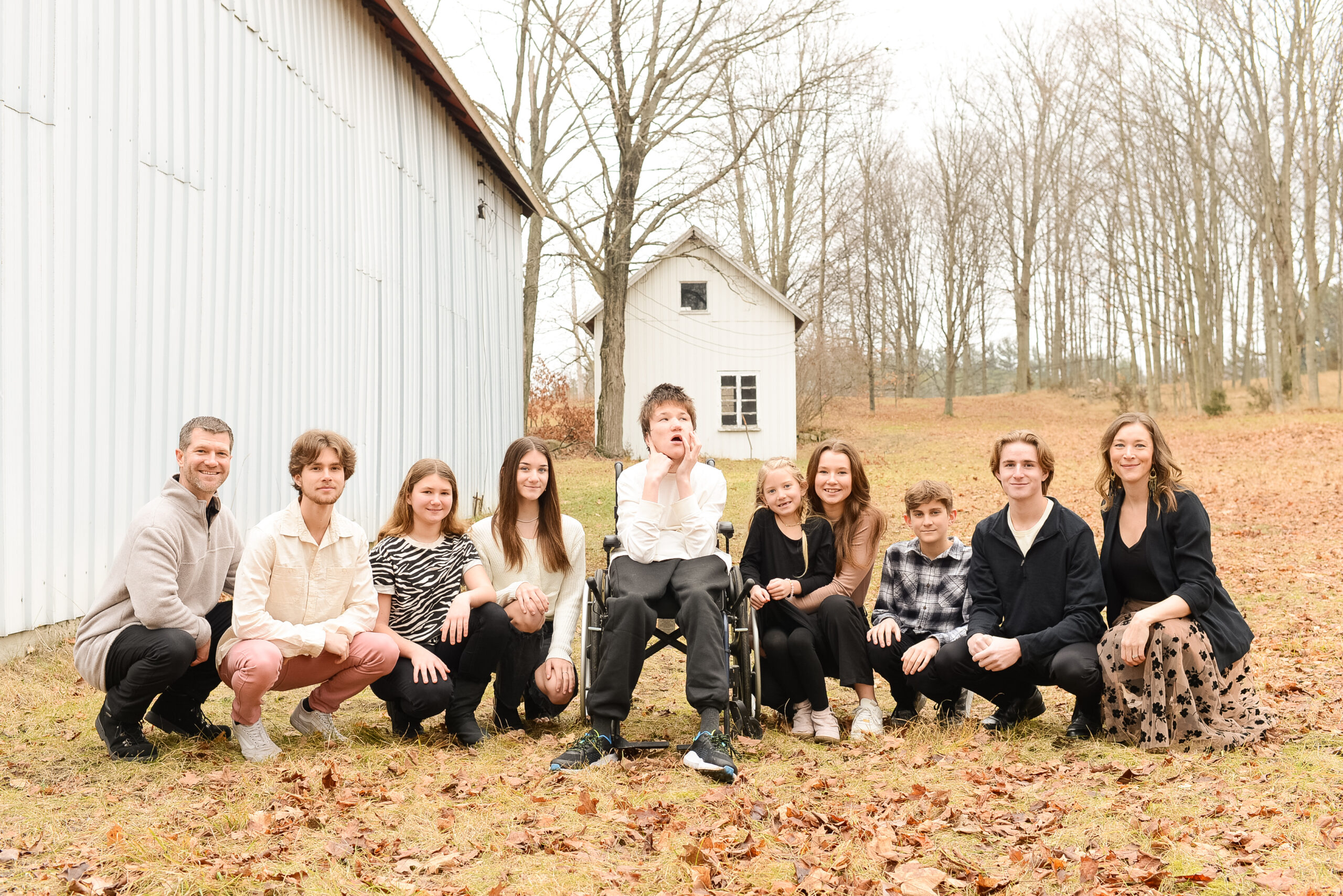 Jess Ronne, Ryan Ronne, and the Ronne family, including Lucas Ronne in the middle. The family is sitting in fall leaves, with Hope Farm in the background.